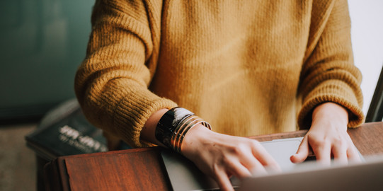 Woman sits at the laptop and types something.