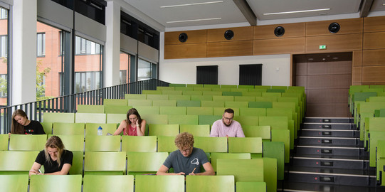 Four students are sitting in a lecture hall.