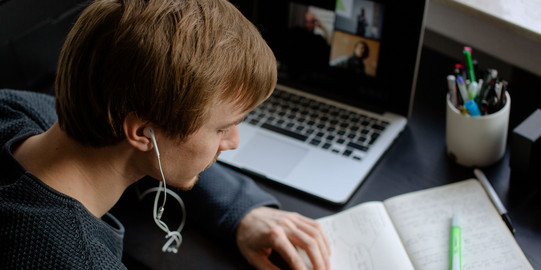 Lernen mit verschiedenen Medien Ein Student arbeitet mit Laptop und Notizbuch.